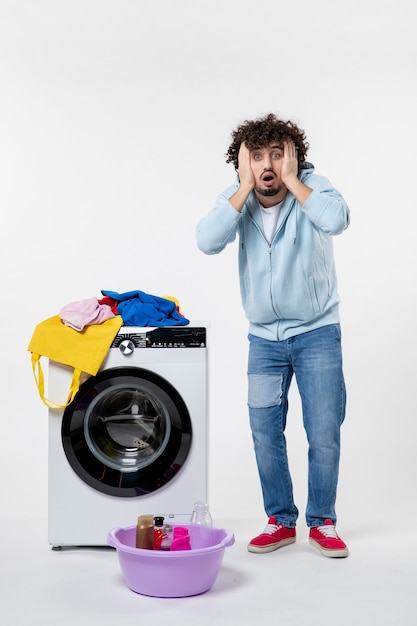 Free photo front view of young male with washer and dirty clothes on white wall