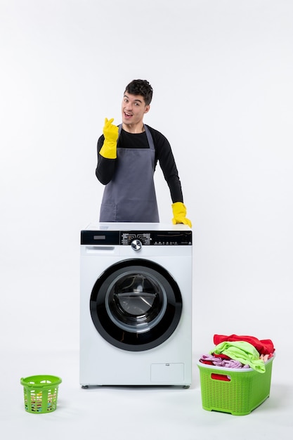 Free photo front view of young male with washing machine and dirty clothes on a white wall