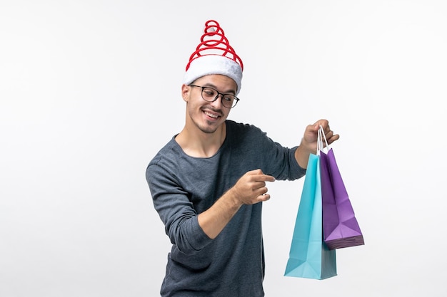 Front view of young man after holiday shopping on white wall