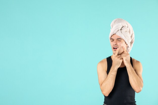 front view of young man after shower on blue wall