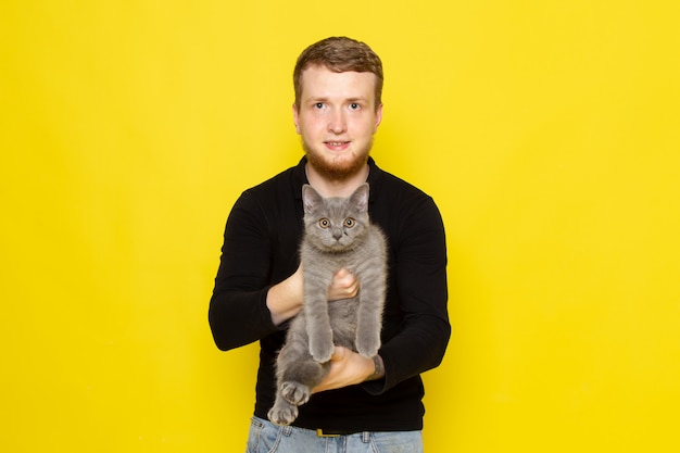 Free Photo front view of young man in black shirt holding cute grey kitten with smile