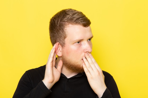 Front view of young man in black shirt posing and trying to heart out with shock