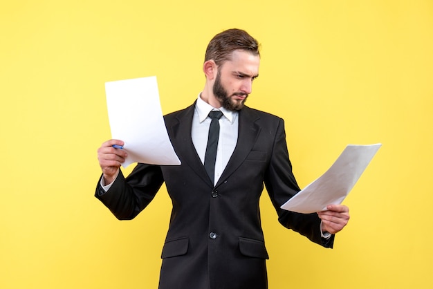 Free photo front view of young man businessman considers carefully each document on yellow