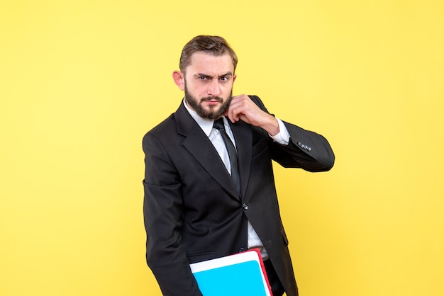 Front view of young man businessman looking wistfully and holding folders on yellow