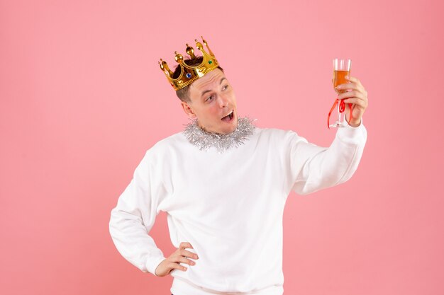 Front view of young man celebrating christmas with drink on pink wall