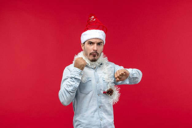 Front view of young man checking time on red wall