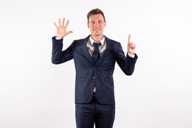 Free photo front view young man in elegant classic suit showing his hand and finger on white background