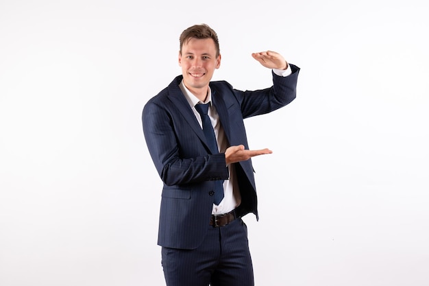 Front view young man in elegant classic suit showing size with his hands on white background