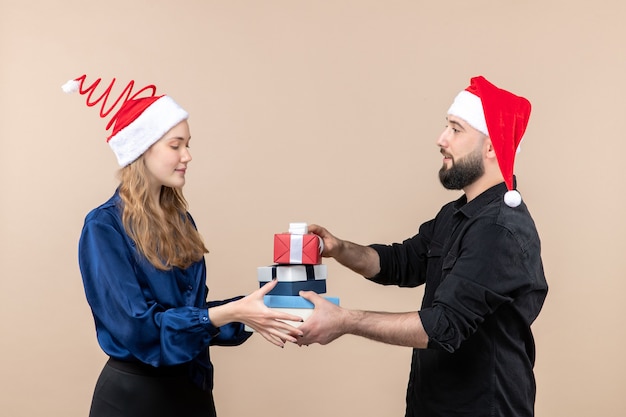 Free photo front view of young man holding christmas presents with woman on pink wall