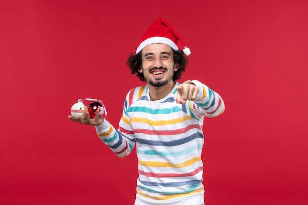 Front view young man holding christmas tree toys on red wall holiday red human