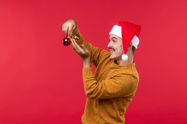 Free Photo front view of young man holding plastic toys on a red wall