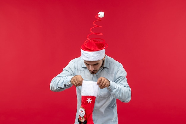 Free Photo front view of young man looking for presents on red wall