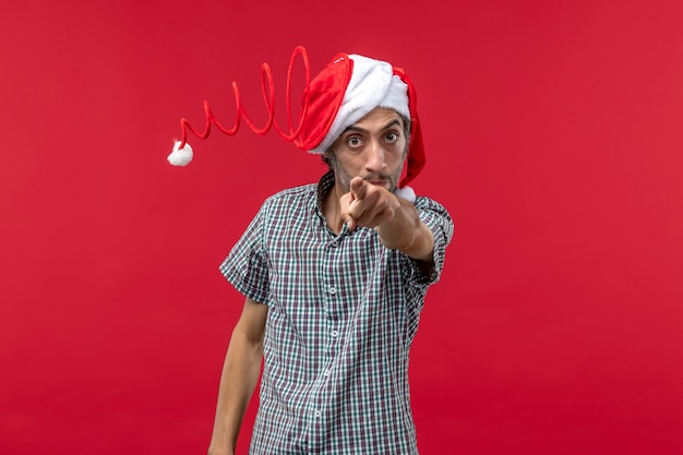 Free Photo front view of young man pointing at you on red wall