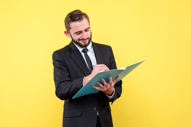 Front view of young man satisfied businessman checking documents in blue folder on yellow