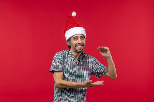 Free photo front view of young man showing size with smile on red wall