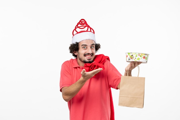 Front view of young man smiling with delivery food on white wall