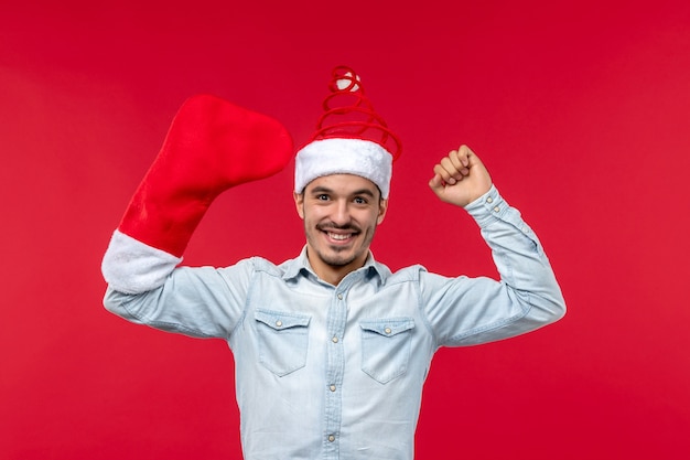 Free photo front view of young man wearing big red sock on red wall