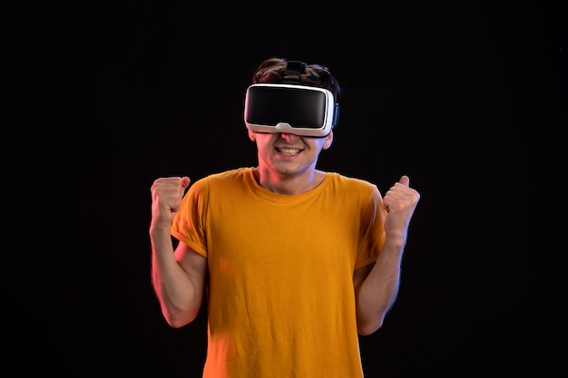 Front view of young man wearing vr headset on a dark wall