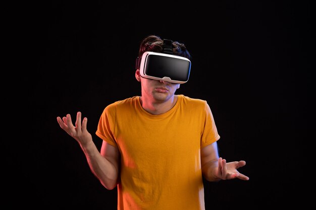 Front view of young man wearing vr headset on dark wall