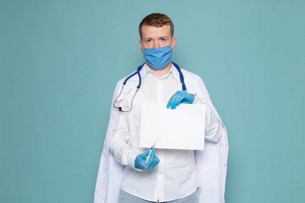 Free photo a front view young man in white shirt and blue gloves with blue mask on the blue space