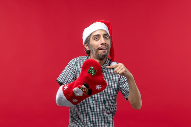 Free Photo front view of young man with christmas sock on red wall