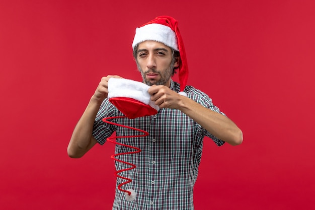 Front view of young man with christmas toy cap on the red wall