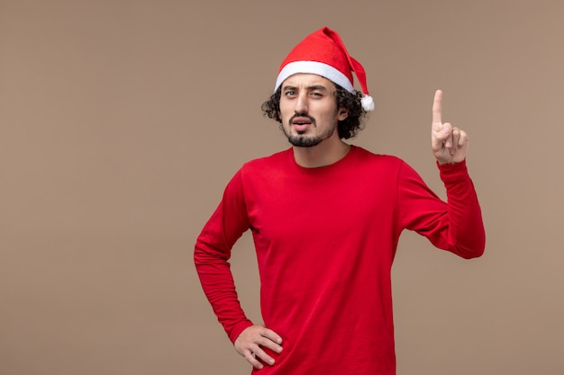 Front view young man with confused face on the brown background holiday christmas emotion