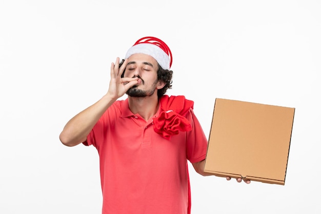 Front view of young man with delivery food box on a white wall