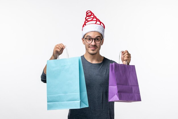 Front view of young man with holiday packages on white wall