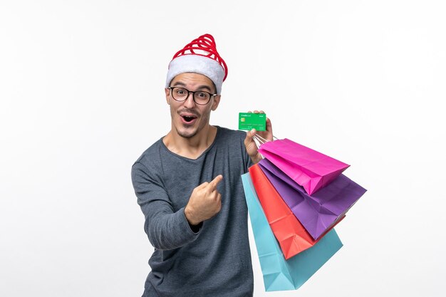 Front view of young man with holiday packages on white wall