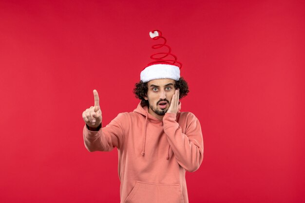 Front view of young man with nervous expression on red wall