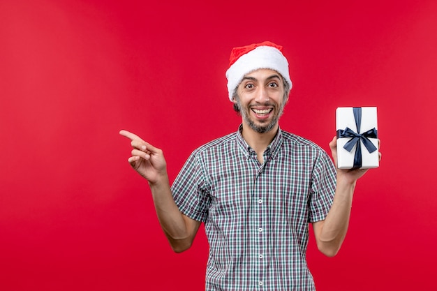 Front view young man with new year present on red background