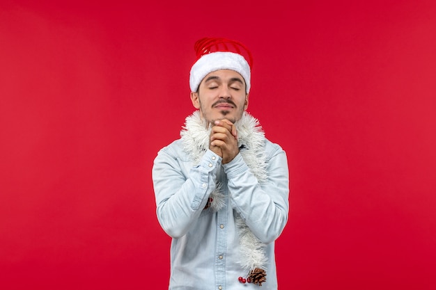 Front view of young man with praying expression on red wall