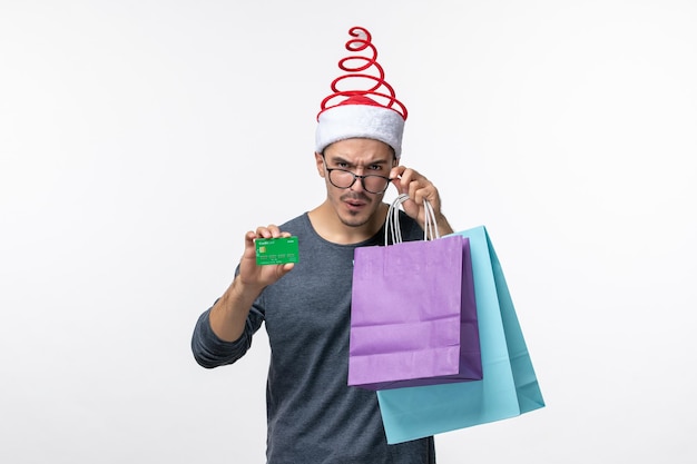 Front view of young man with presents and bank card on a white wall