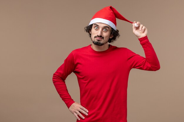 Front view young man with red christmas cape on brown background holiday christmas emotion