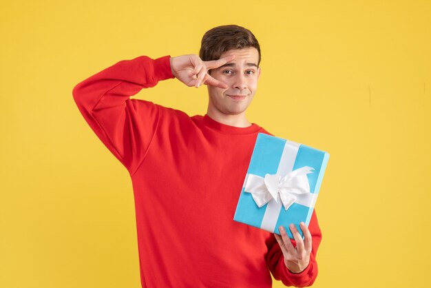 Front view young man with red sweater standing on yellow background