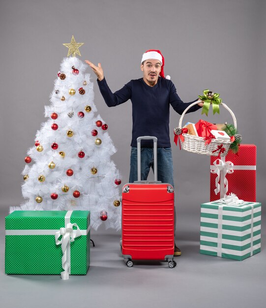 Front view young man with santa hat holding gift basket on grey isolated