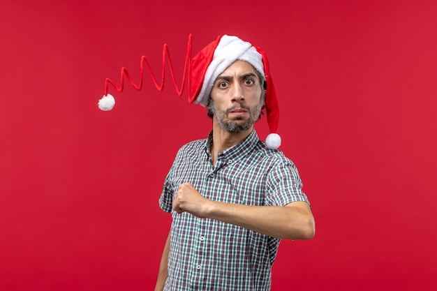 Front view of young man with serious expression on red wall