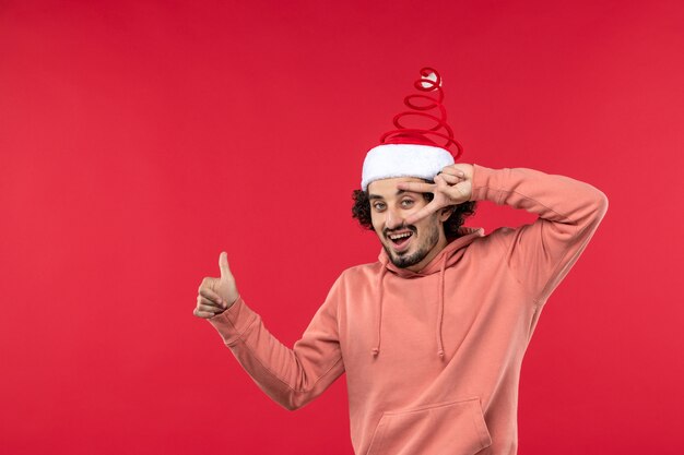 Front view of young man with smiling face on red wall