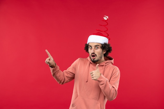 Front view of young man with surprised expression on red wall