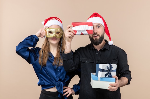 Front view of young man with woman holding presents on pink wall