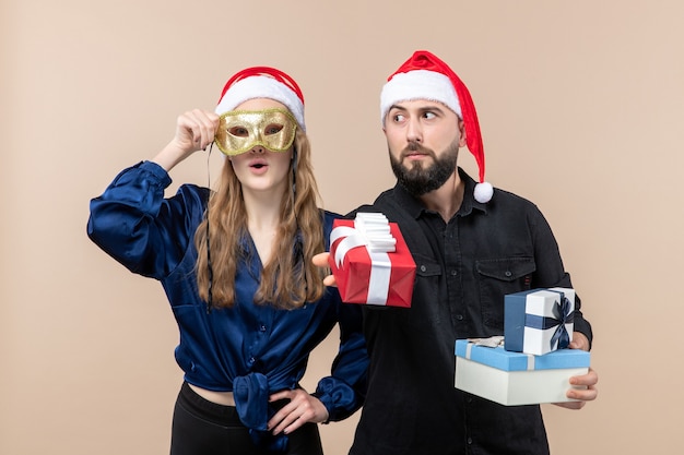 Front view of young man with woman holding presents on pink wall