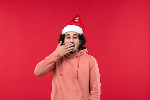 Front view of young man with yawning expression on red wall