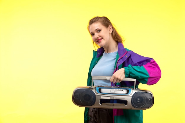 Free photo a front view young modern woman in blue shirt black trousers colorful jacket smiling posing holding tape-recorder