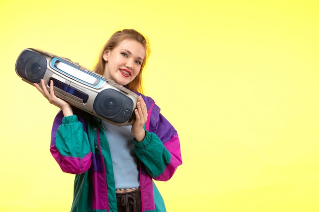 Free photo a front view young modern woman in blue shirt black trousers colorful jacket smiling posing holding tape-recorder