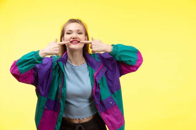 A front view young modern woman in blue shirt black trousers colorful jacket smiling posing