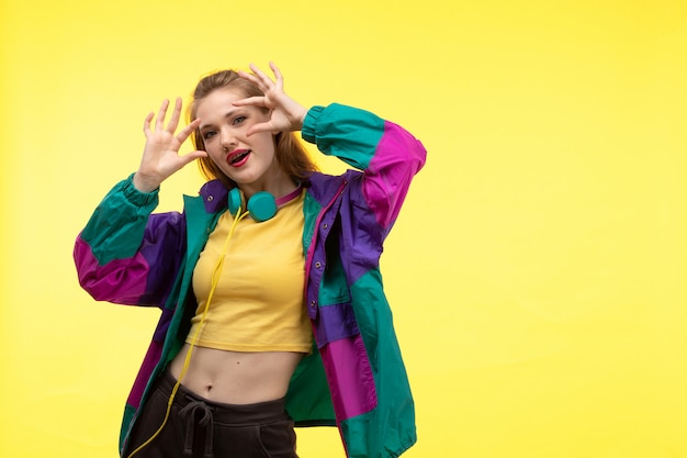 Free Photo a front view young modern woman in yellow shirt black trousers and colorful jacket with colored earphones posing