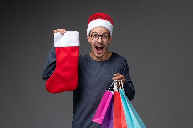 Front view of young person after holiday shopping on a dark wall