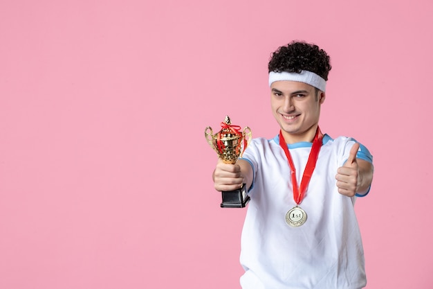 Free photo front view young player in sport clothes with golden cup on pink wall