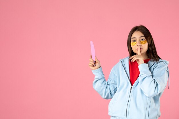 front view young pretty female with eye patches and nail file on pink background